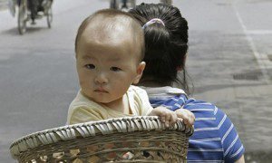 A baby is carried in a basket on her mother's back on a street in Beijing, China